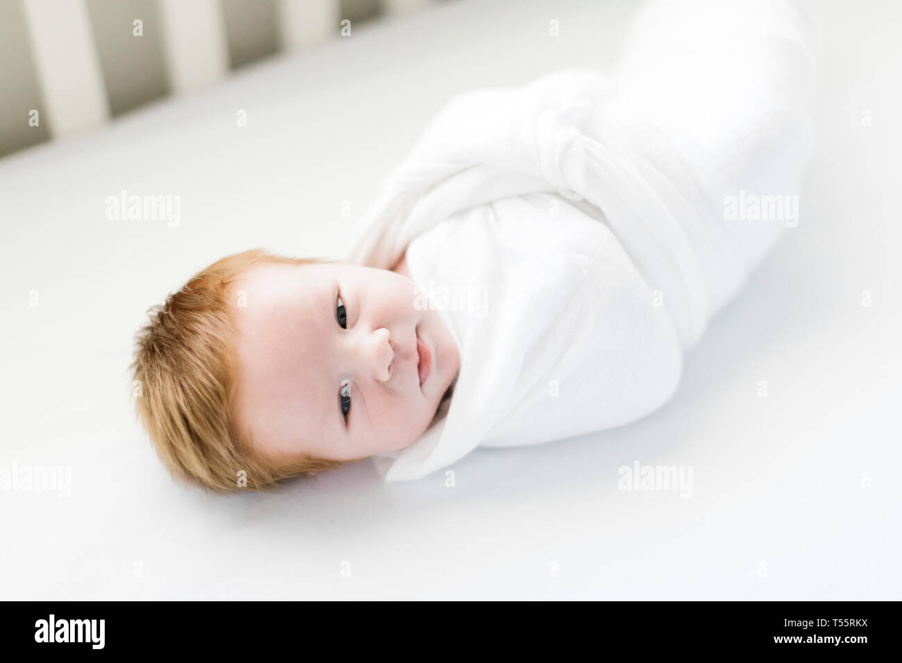 Swaddled baby boy in cot Stock Photo Alamy