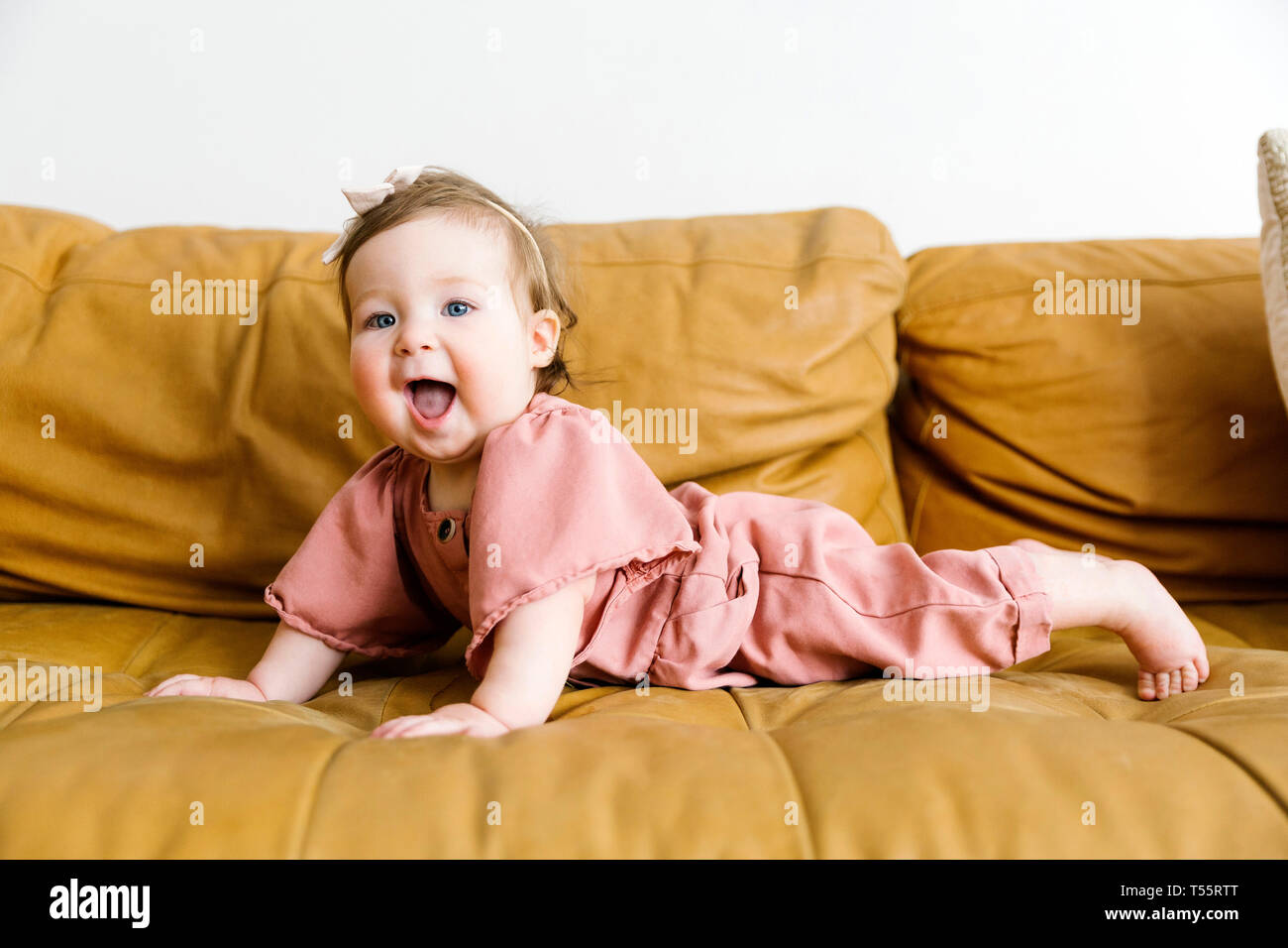 Baby girl wearing pink outfit on sofa Stock Photo