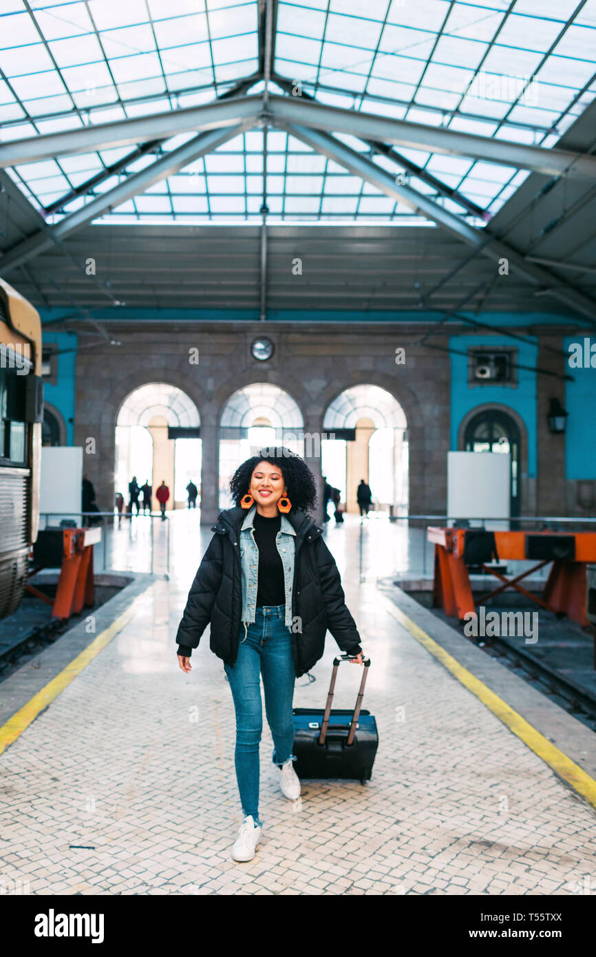 Young woman pulling suitcase in railway station Stock Photo - Alamy