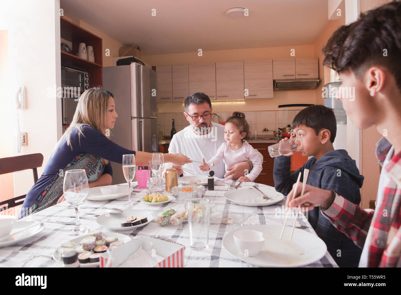 Family eating sushi at dining table Stock Photo