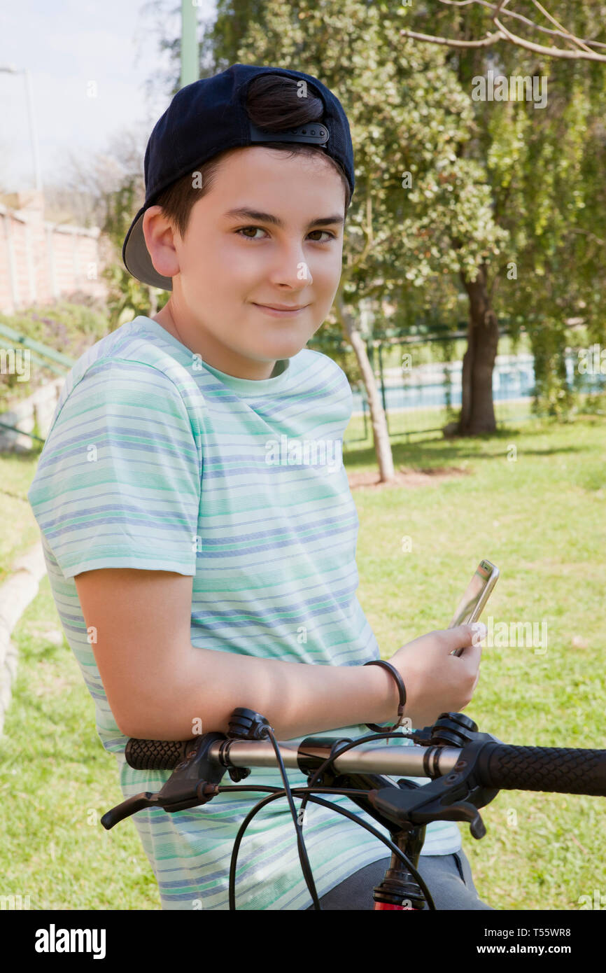 Teenage boy holding smart phone with his bicycle Stock Photo