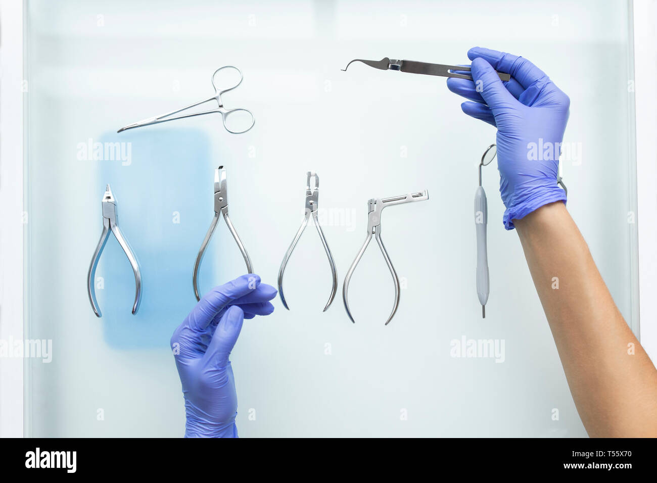 Hands of dental assistant wearing rubber gloves with dental equipment