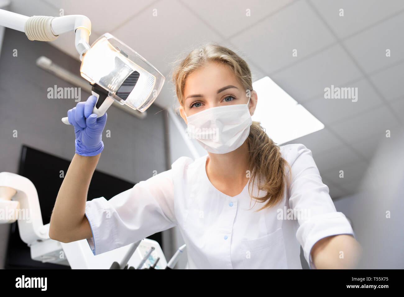 Patient point of view of dental assistant holding light Stock Photo