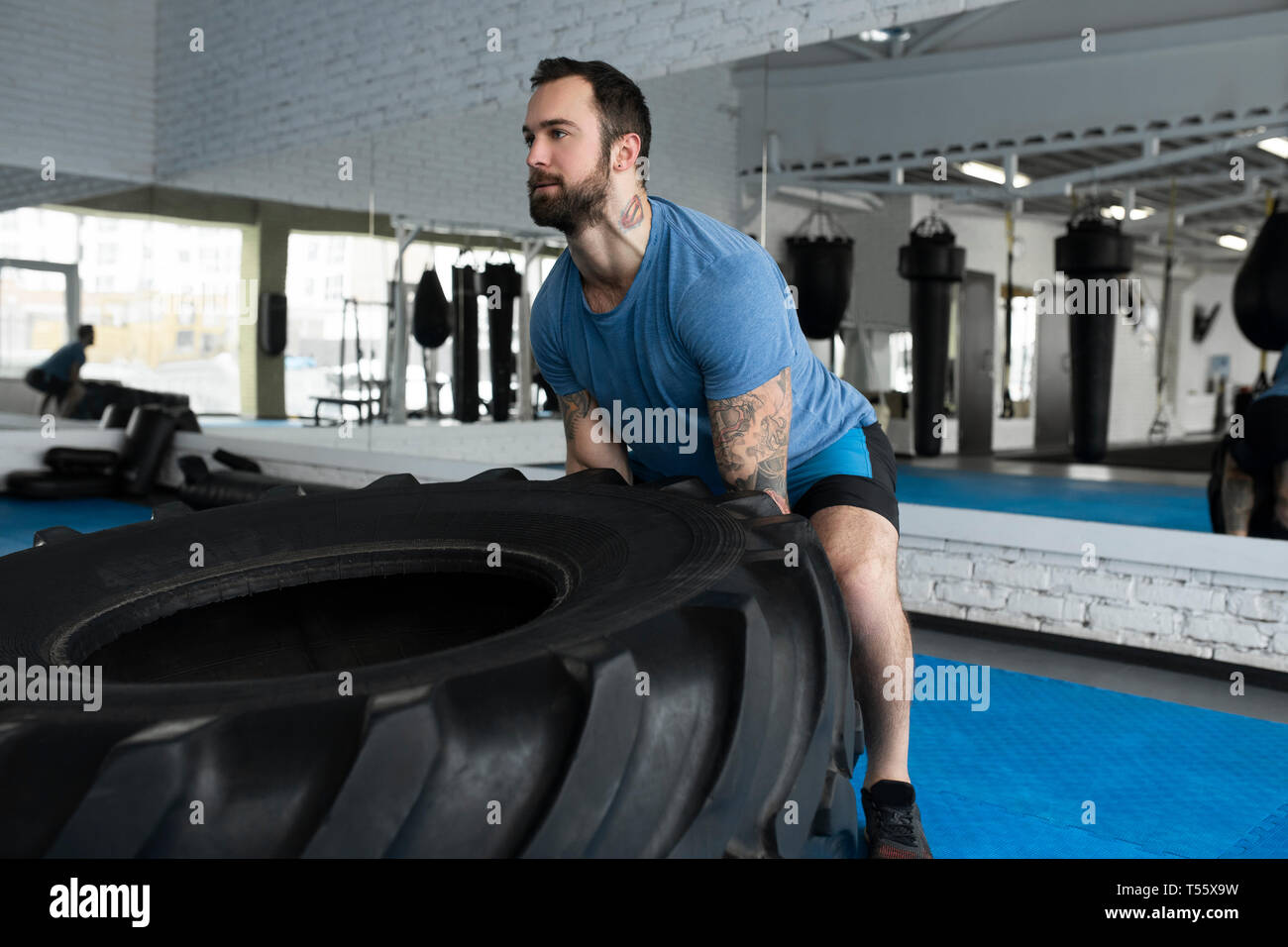 Mid adult man lifting tire in gym Stock Photo