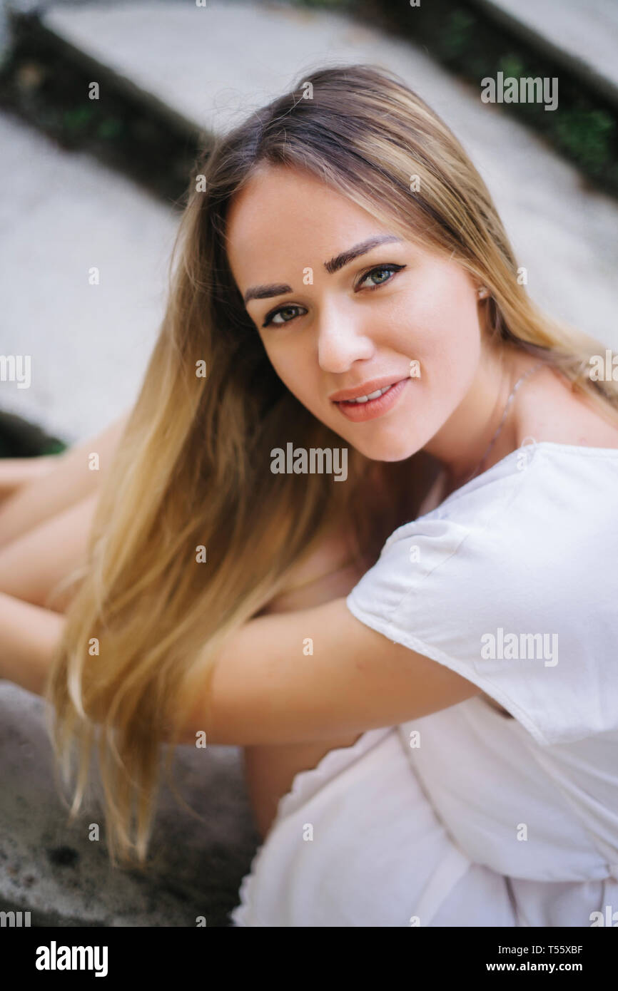 Young woman with dyed blond hair sitting on steps Stock Photo