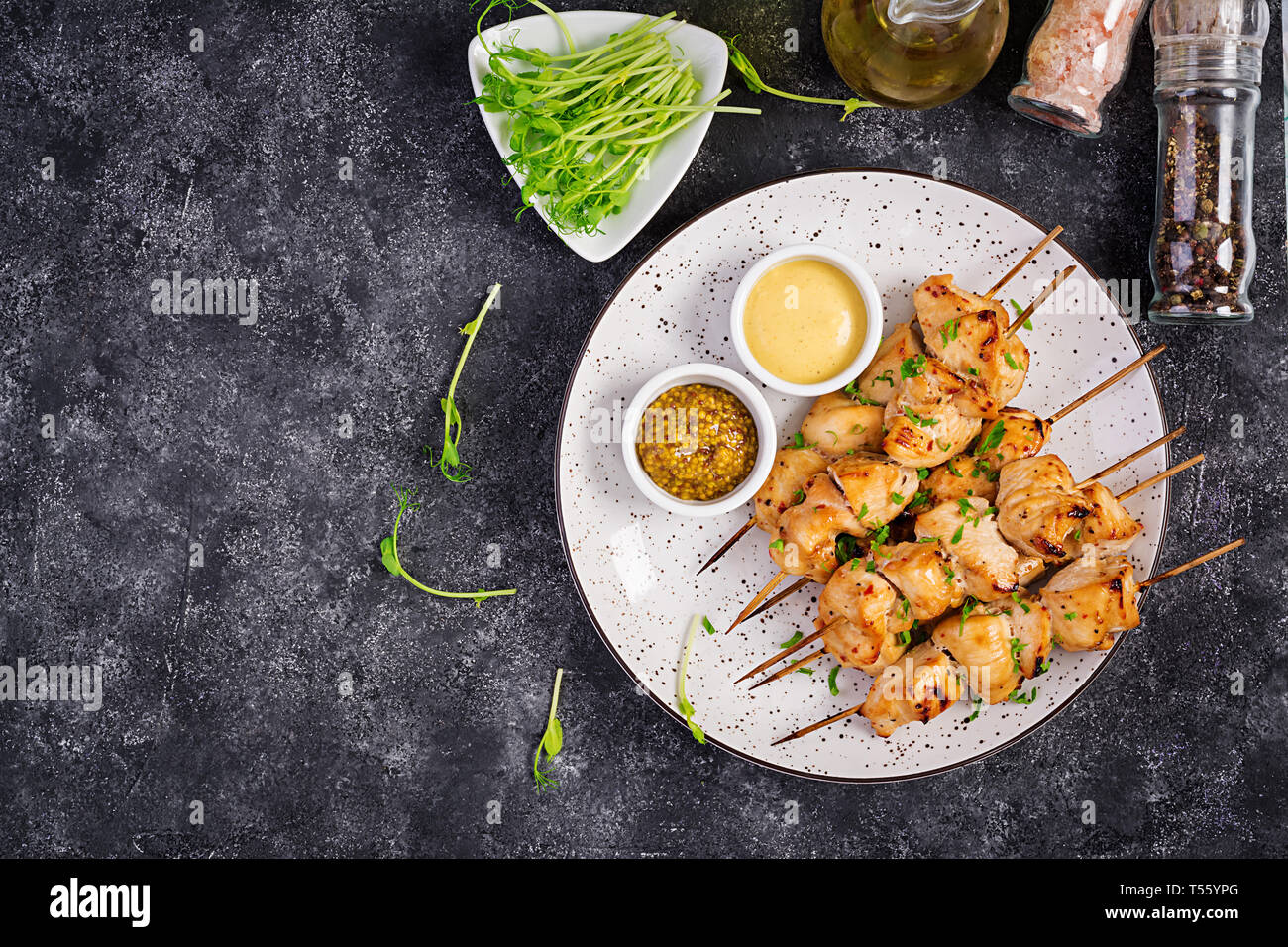 Grilled chicken kebab and salad with cucumber, radish, onion on a dark