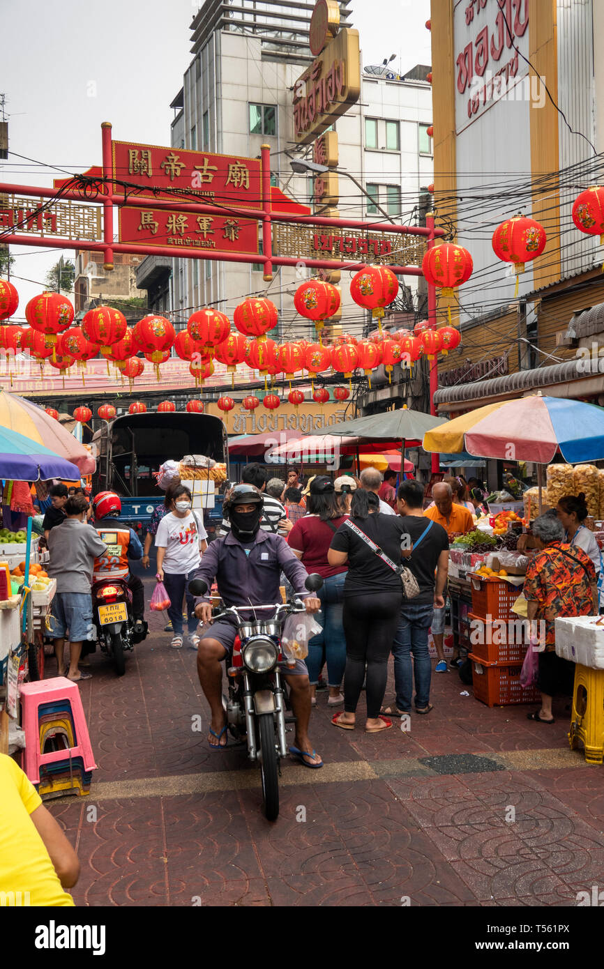 Thailand, Bangkok, Chinatown, Thanon Mangkon, man riding motorcycle through crowded shopping street Stock Photo