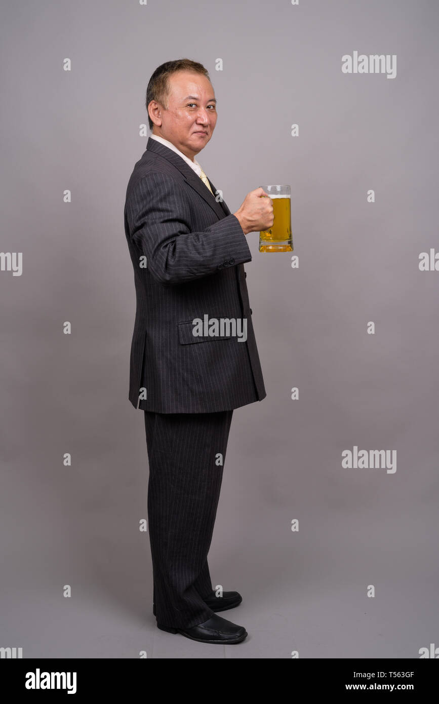 Portrait of mature Asian businessman against gray background Stock Photo