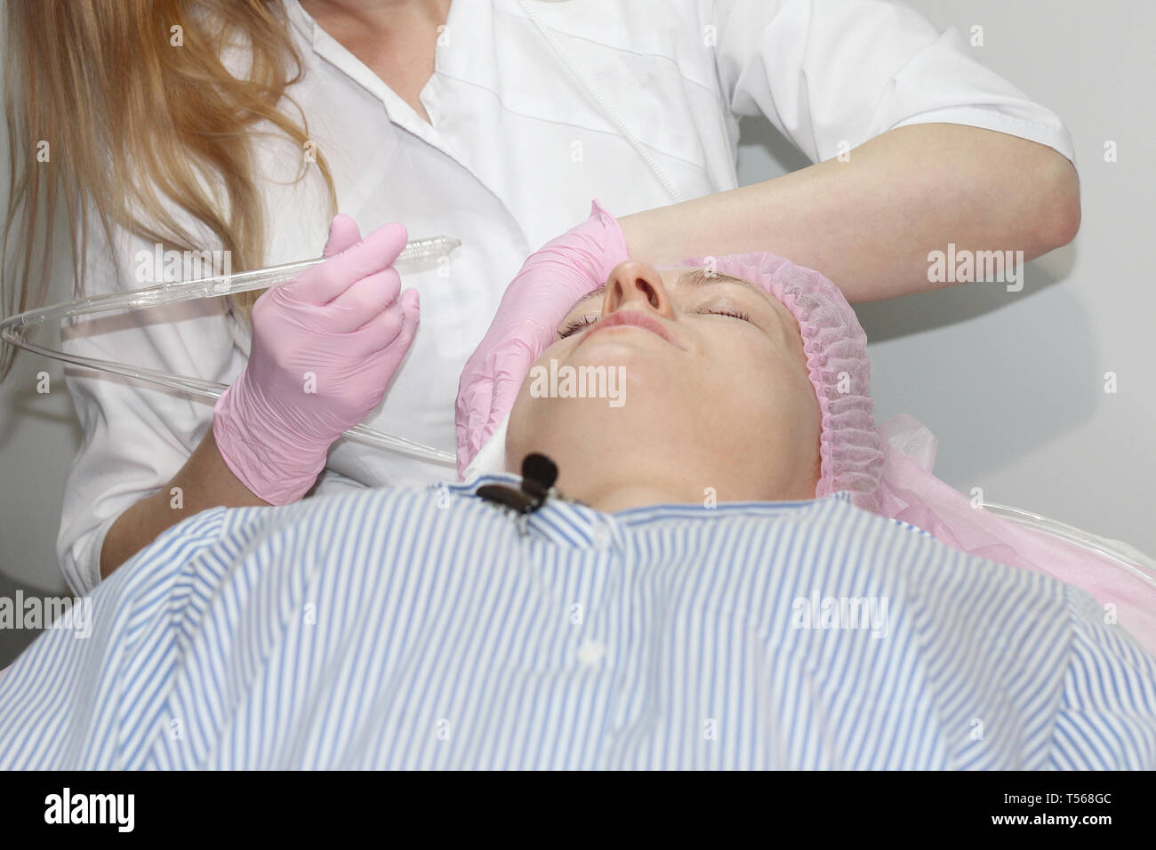 Beautician makes facial rejuvenation of women. Gas-liquid peeling procedure, face aquapiling. Stock Photo