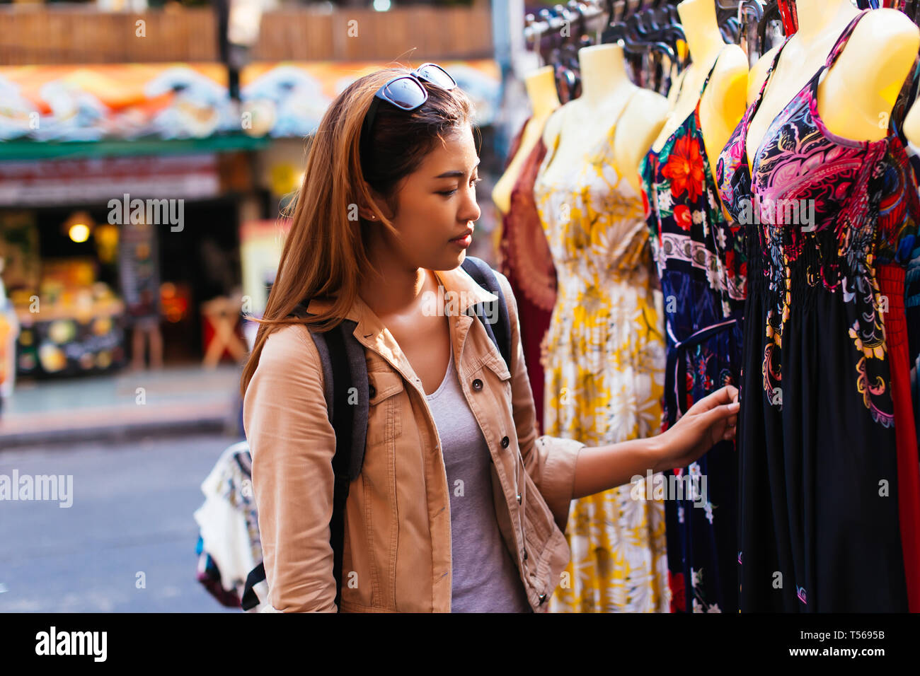 Young female Asian tourist woman shopping and choosing clothes on