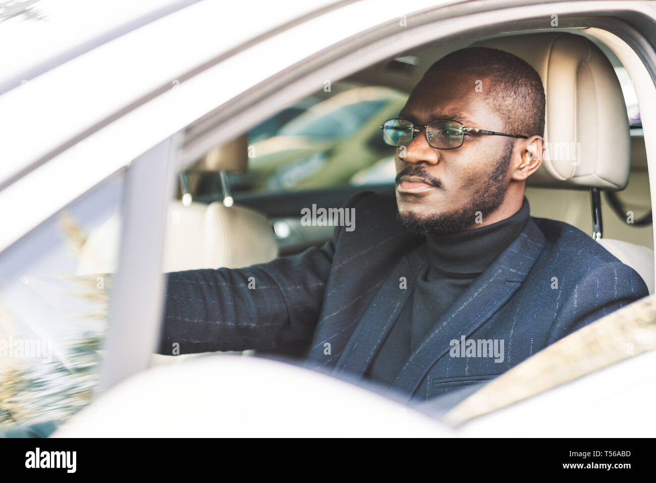 A young businessman in a suit sits at the wheel of a expensive car. Stock Photo
