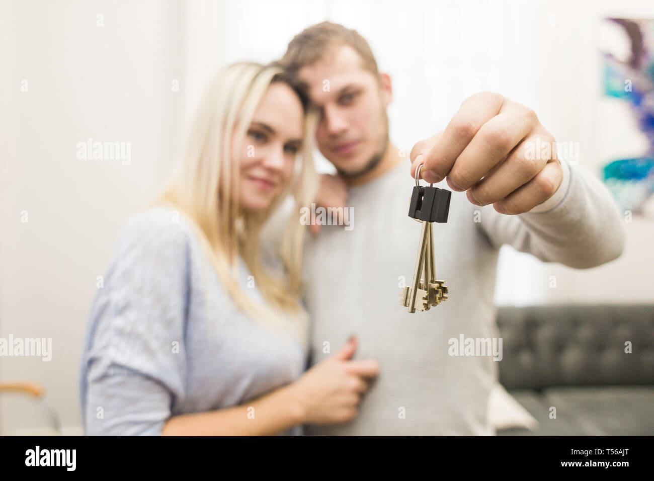 A lovely young couple holds in front of them the keys to their new ...