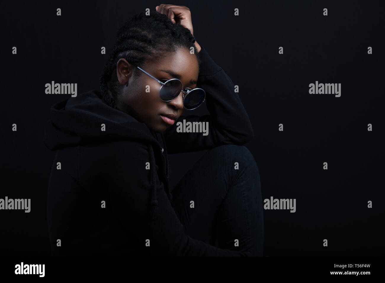 Cool african woman sitting with dark skin wearing round sunglasses