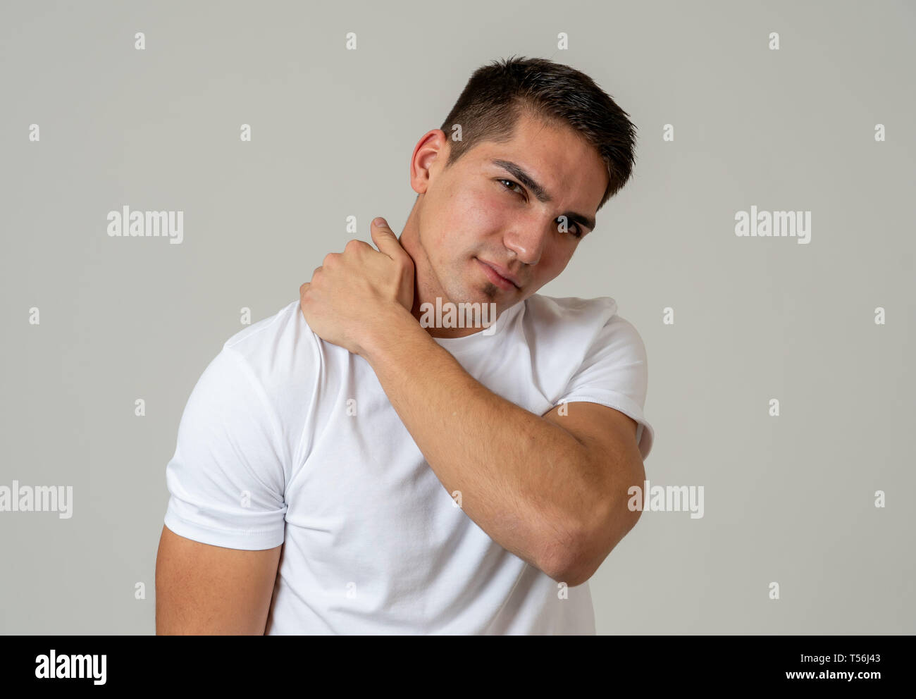 Young muscular fitness man touching and grabbing his neck and upper back suffering cervical pain isolated on neutral background. In sport injury Incor Stock Photo