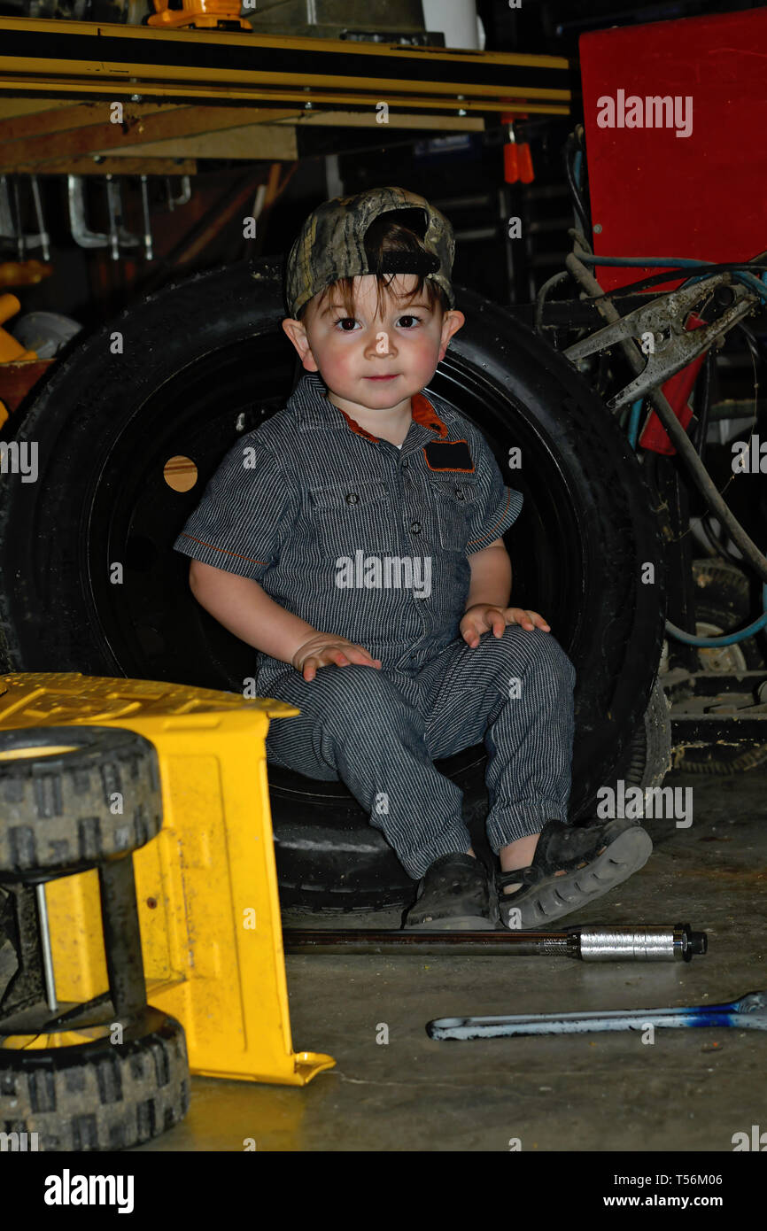 Little boy dressed as a mechanic working in a garage Stock Photo