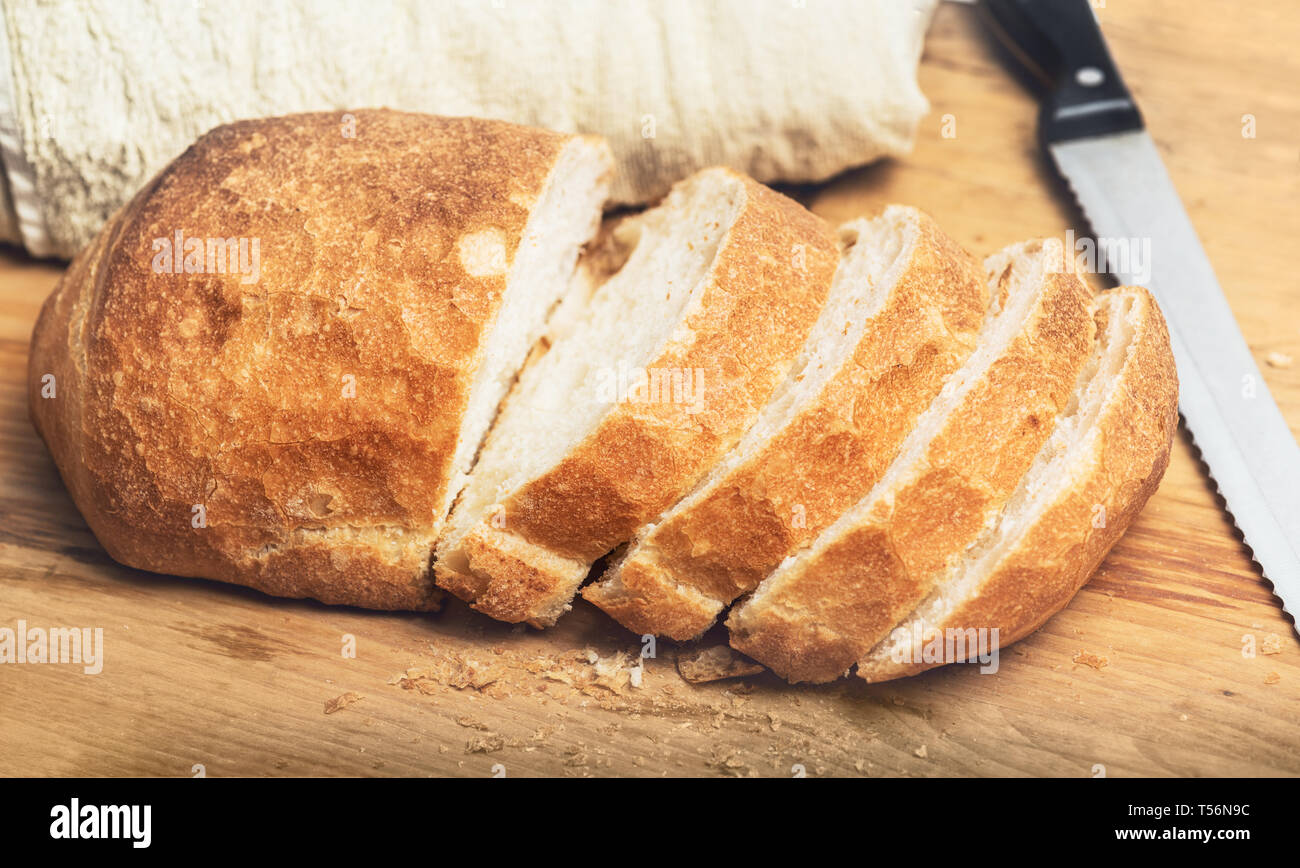 Ciabatta bread loaf slices on wooden board with knife. Fresh crusty white whreat bread italian cuisine Stock Photo