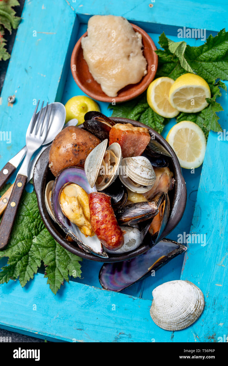 Famous traditional dish of the south of Chile and the Chiloe archipelago - Curanto al Hoyo, Kuranto. Different seafood, meat and potatoes milcao Stock Photo