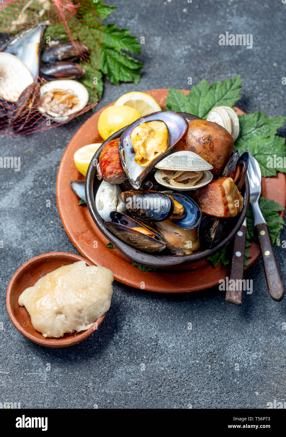 Famous traditional dish of the south of Chile and the Chiloe archipelago - Curanto al Hoyo, Kuranto. Different seafood, meat and potatoes milcao Stock Photo