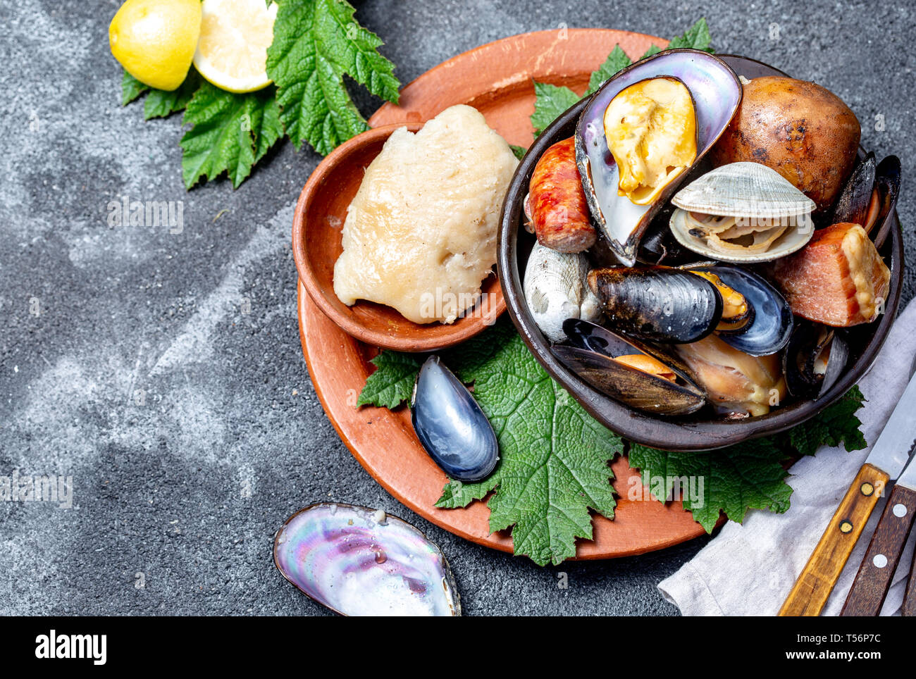 Famous traditional dish of the south of Chile and the Chiloe archipelago - Curanto al Hoyo, Kuranto. Different seafood, meat and potatoes milcao Stock Photo