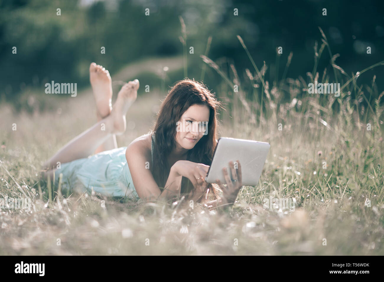 cute girl with digital tablet lying on lawn on summer day. people and ...
