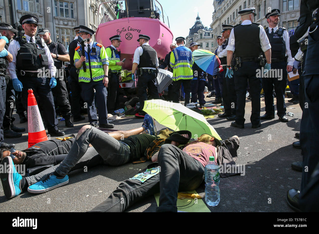 Environmental activists are seen lying on the ground at the Oxford Circus during the fifth day of the climate change protest by the Extinction Rebellion movement group. A large number of police presence around the pink yacht as they un-bond the activists who glued themselves and the police prepares to remove them from the site. According to the Met Police, over 1000 activists have been arrested since the demonstration started on 11 April 2019. Stock Photo