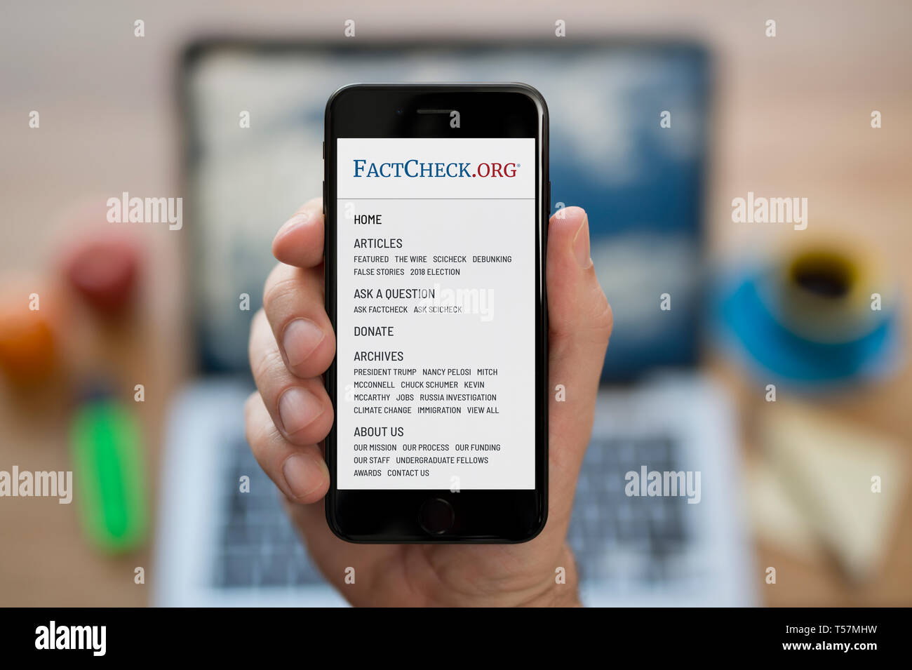 A man looks at his iPhone which displays the FactCheck.org logo (Editorial use only). Stock Photo