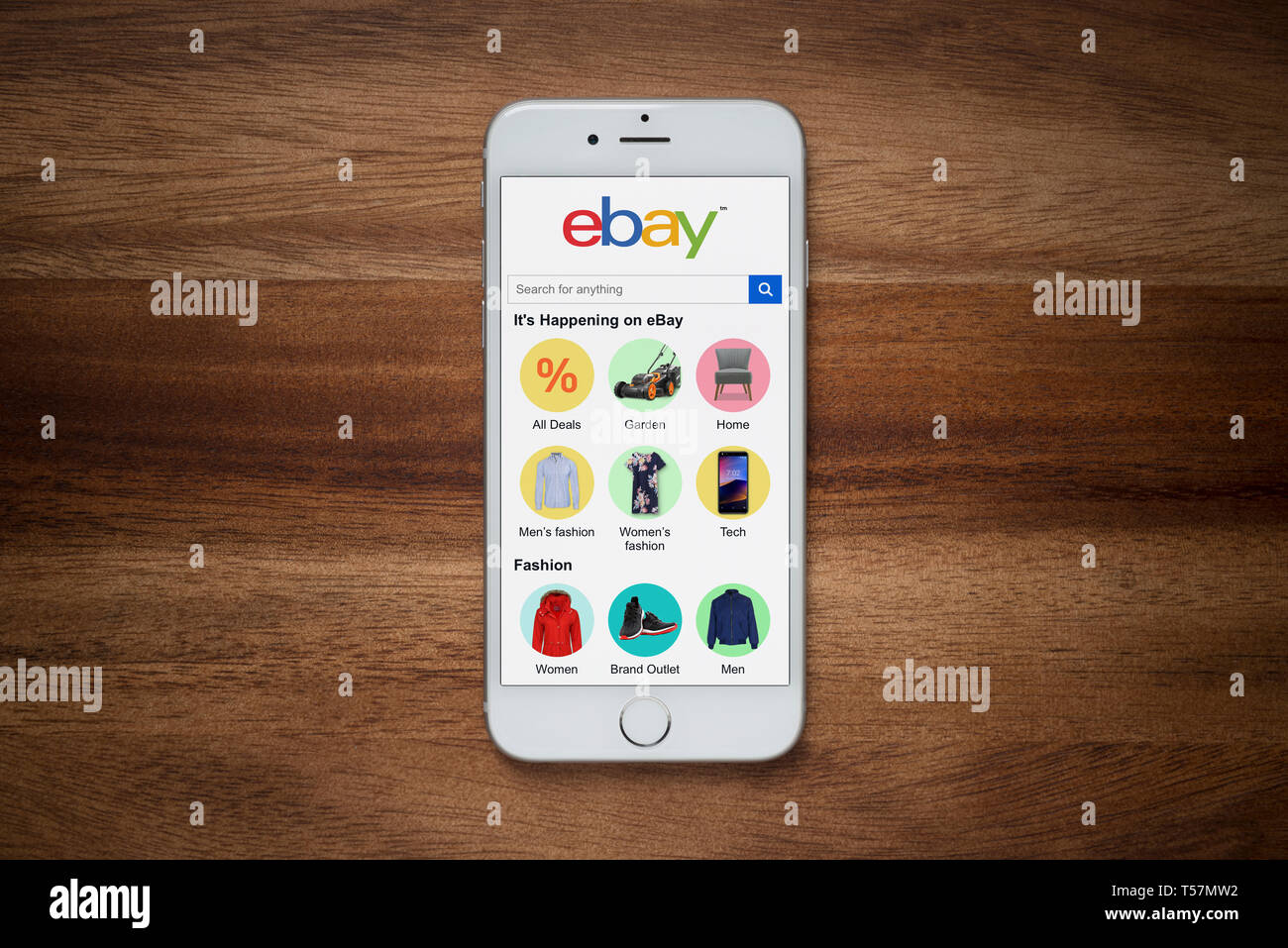 An iPhone showing the ebay website rests on a plain wooden table (Editorial use only). Stock Photo