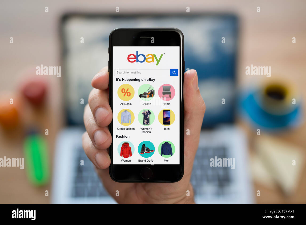 A man looks at his iPhone which displays the ebay logo (Editorial use only). Stock Photo