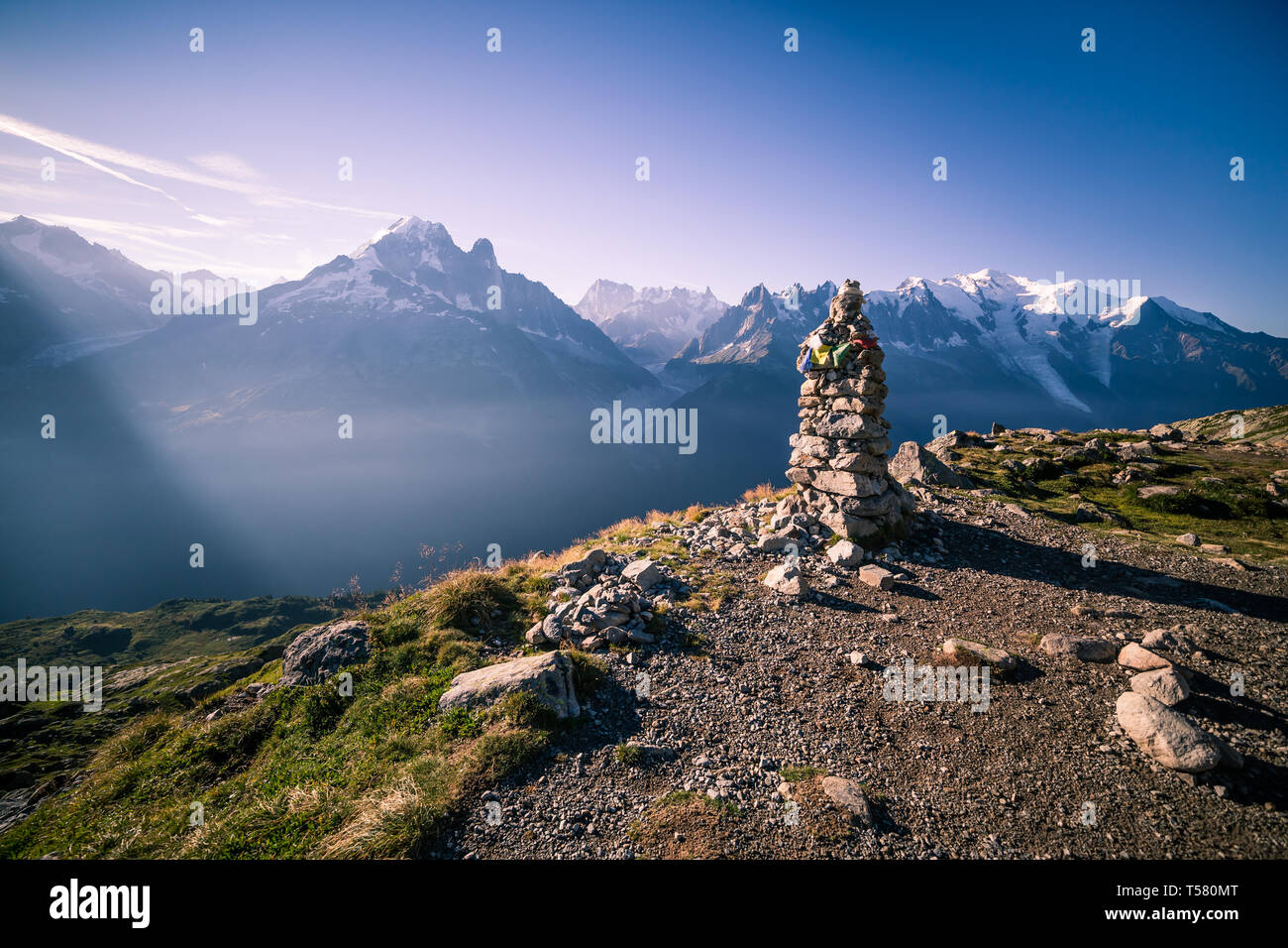 Altitude Cairn and Tibetan Flag in front of Iconic Mont-Blanc Snowy Peaks and Glacier Stock Photo