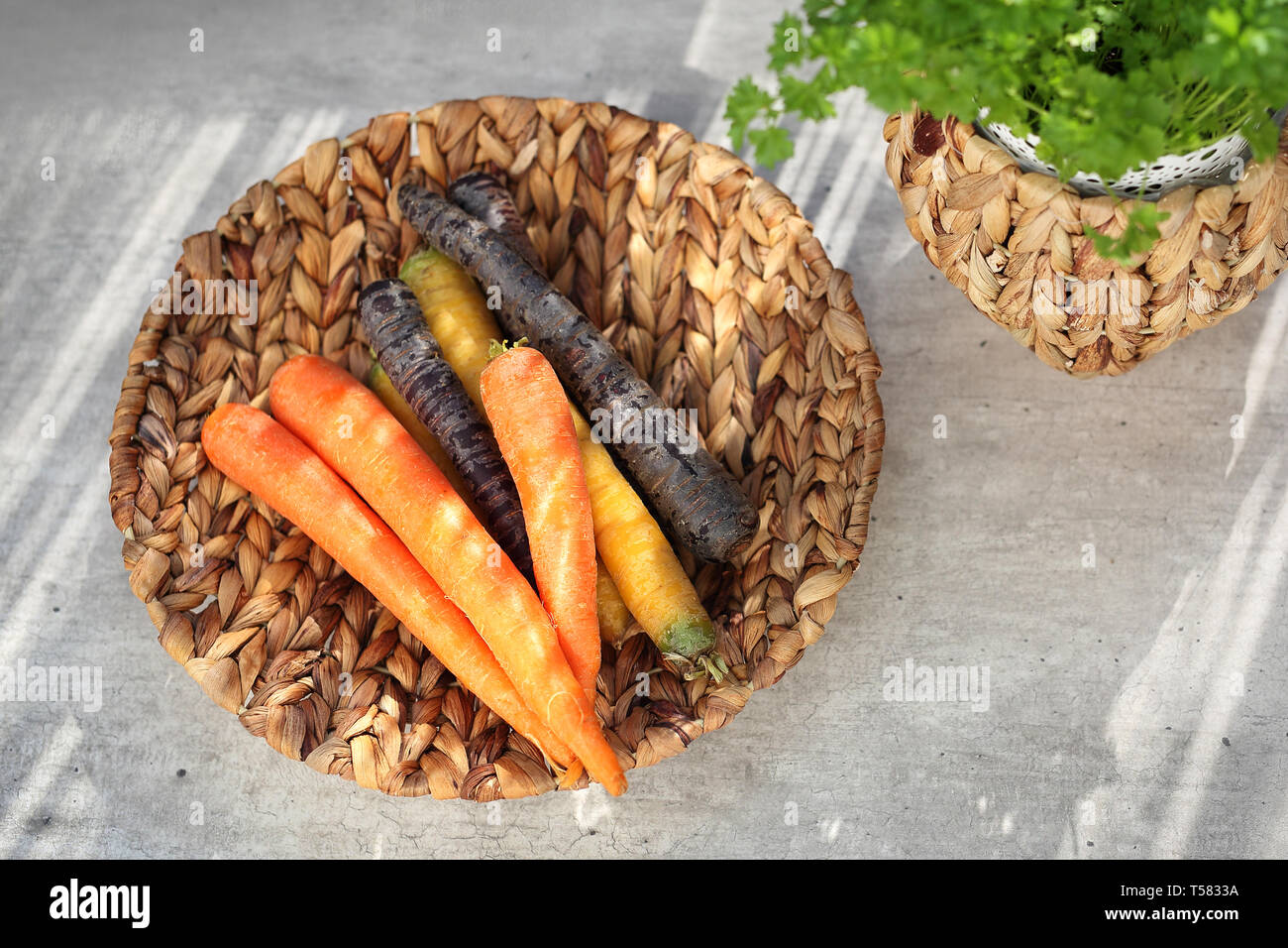 Colorful carrots, yellow, orange and purple. Basket with vegetables on a kitchen counte Stock Photo