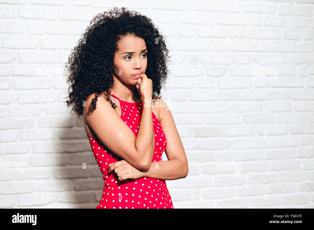 Portrait of worried african american woman against white wall. Black