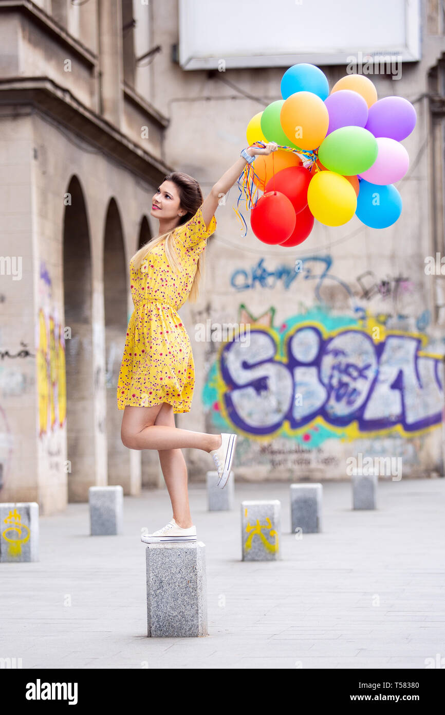 A happy girl with a lot of ballons in hand in the city Stock Photo