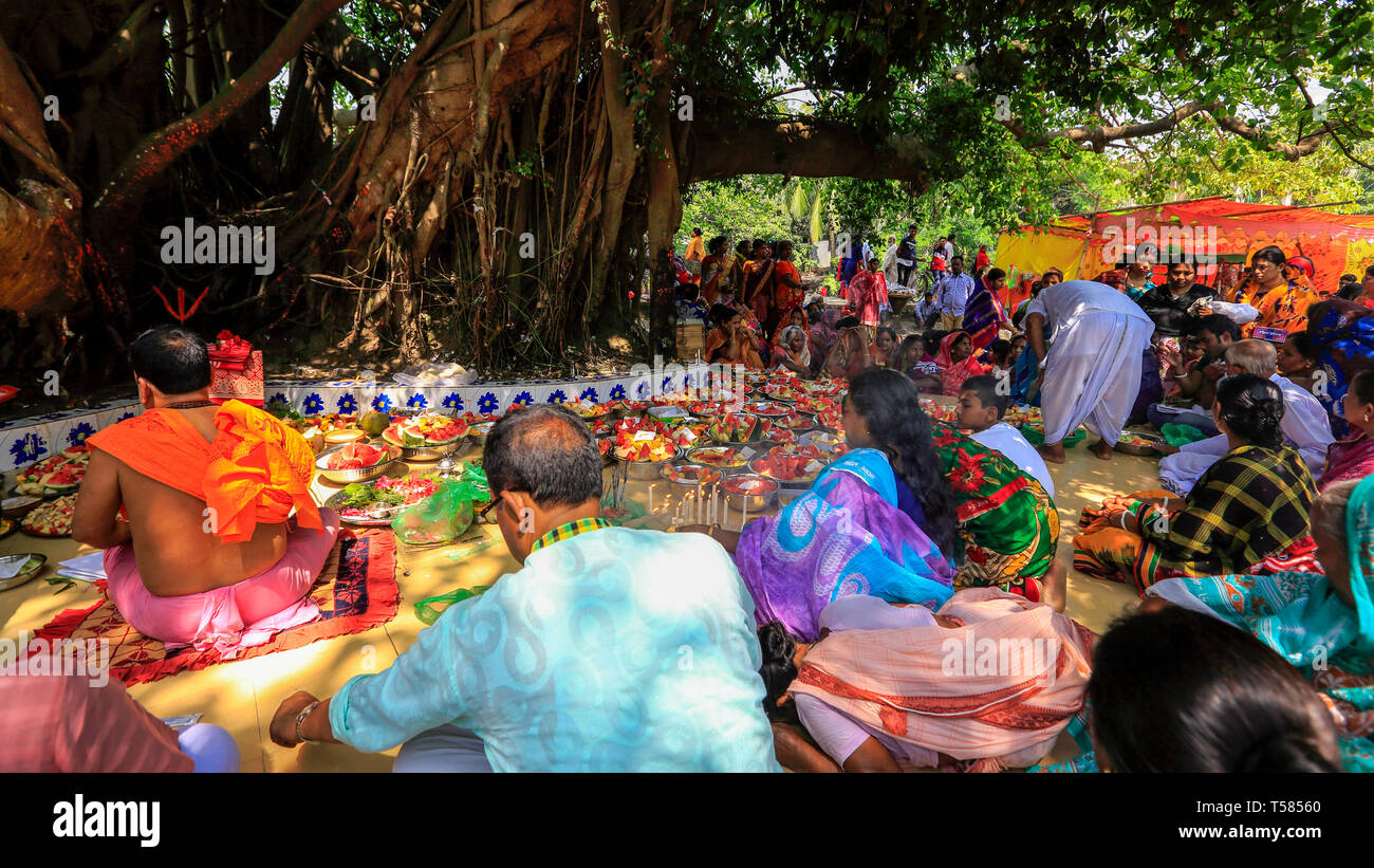 Devotees sit beside arrays of offerings placed under the ancient banyan ...