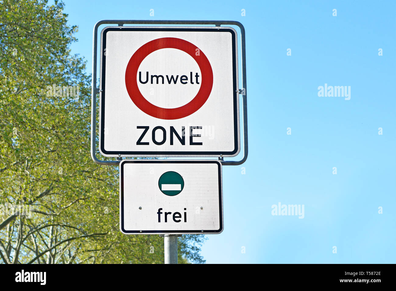 Road traffic sign marking a low emission zone in city centers in Germany translating as "Environmental Zone" and sign green environmental badget Stock Photo