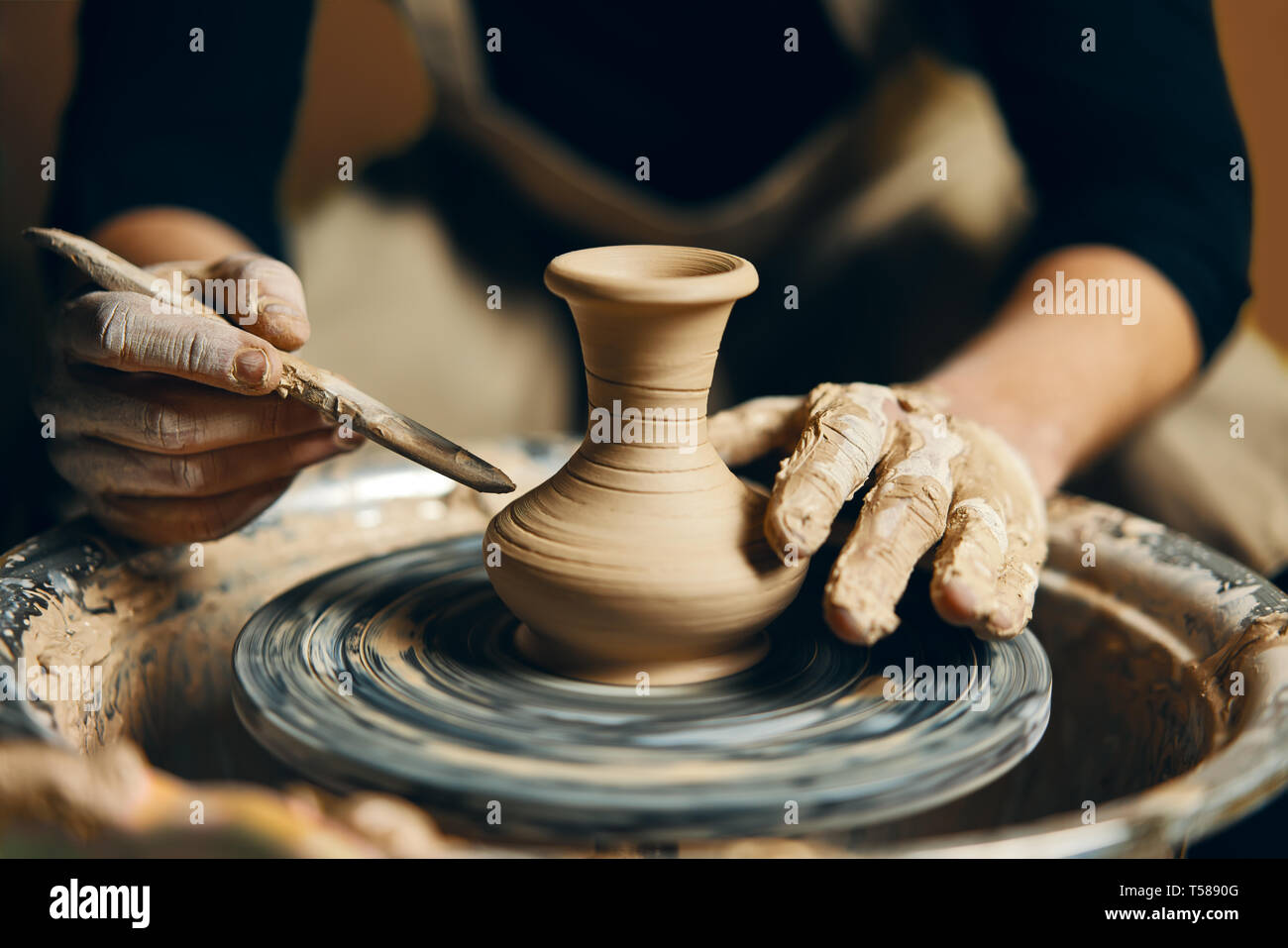Man potter working on potters wheel making ceramic pot from clay in ...