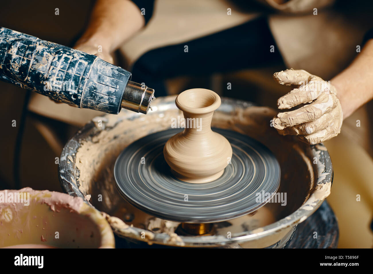Man potter working on potters wheel making ceramic pot from clay in ...
