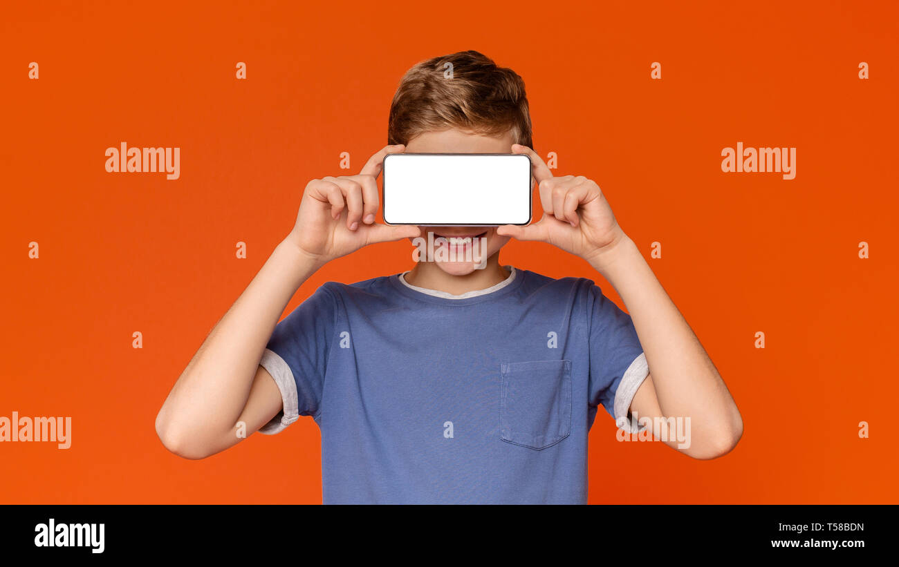 Happy modern teen boy covering eyes with blank smartphone Stock Photo ...