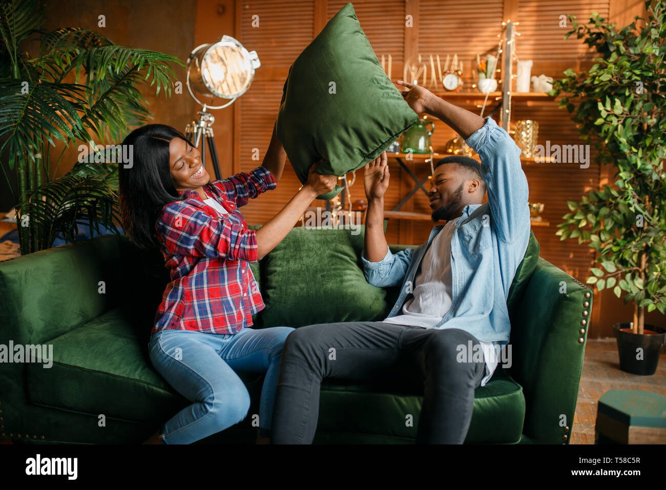 Black couple having fun on sofa, pillow fight Stock Photo - Alamy