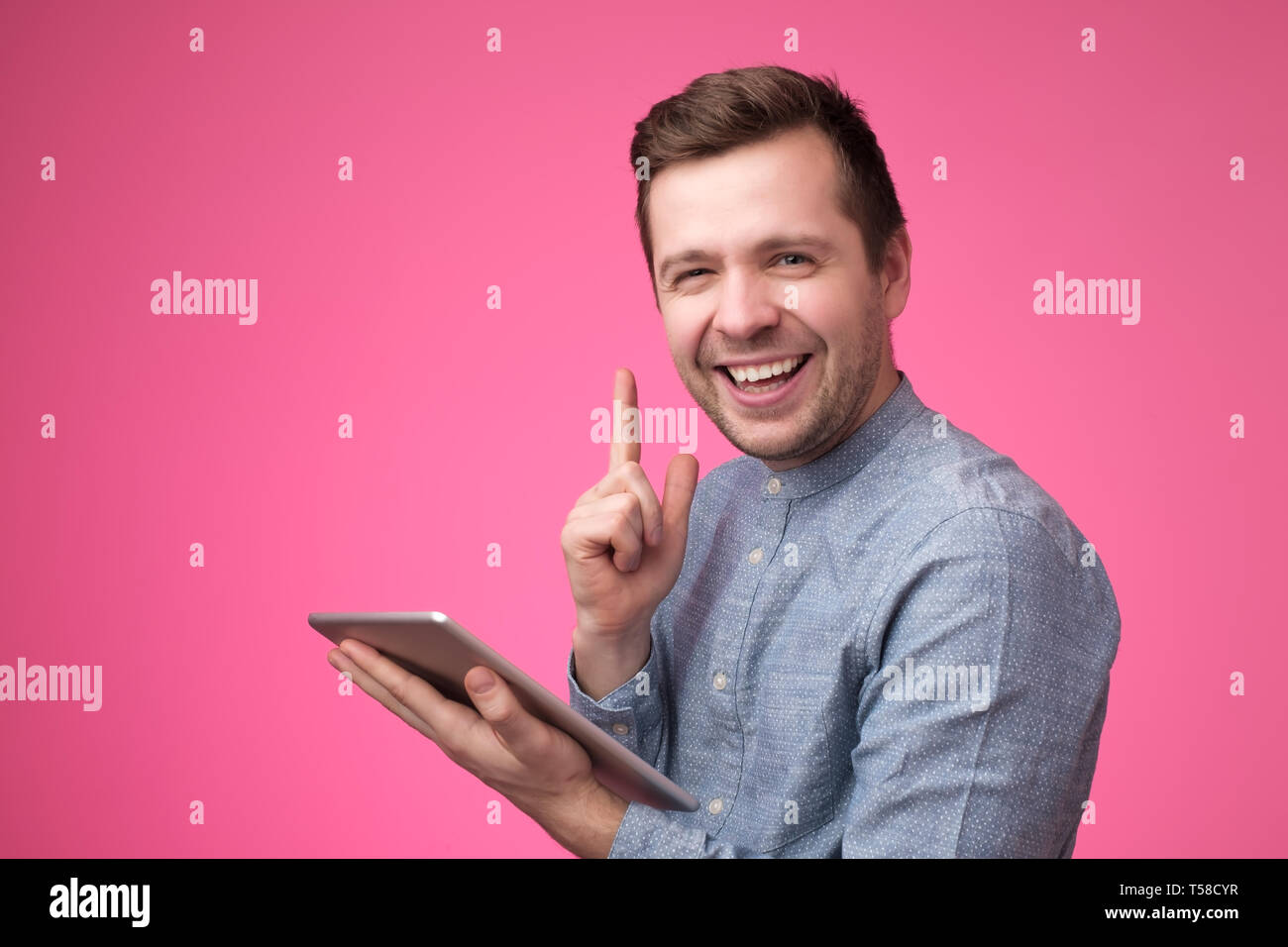 Pensive young man using his digital tablet and giving advice with index finger Stock Photo