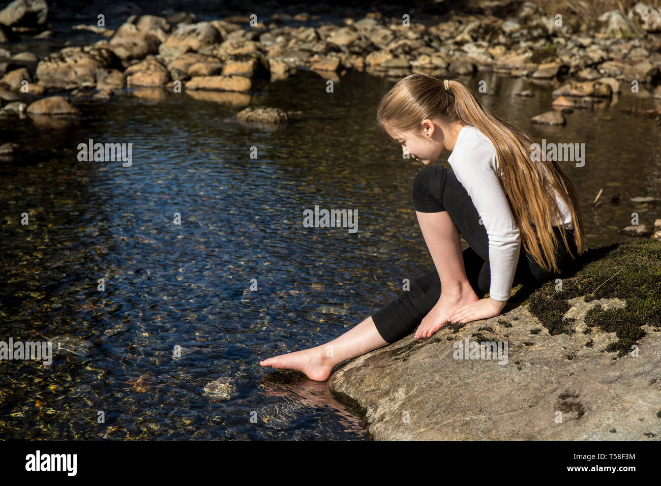 Olallie State Park, near North Bend, Washington, USA. Nine year old girl gingerly testing the