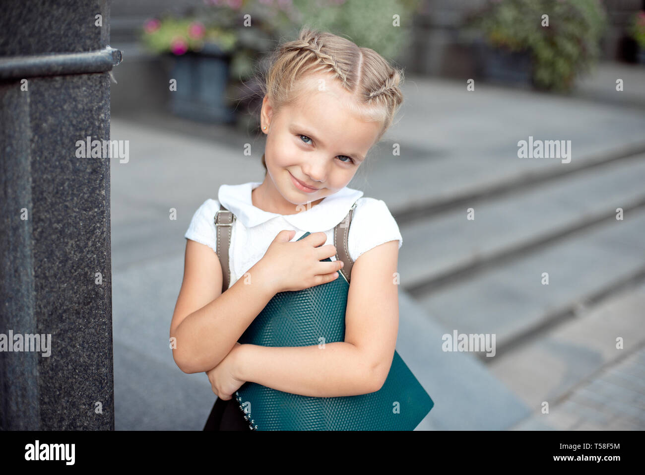 Happy little schoolgirl with book going back to school outdoor Stock Photo