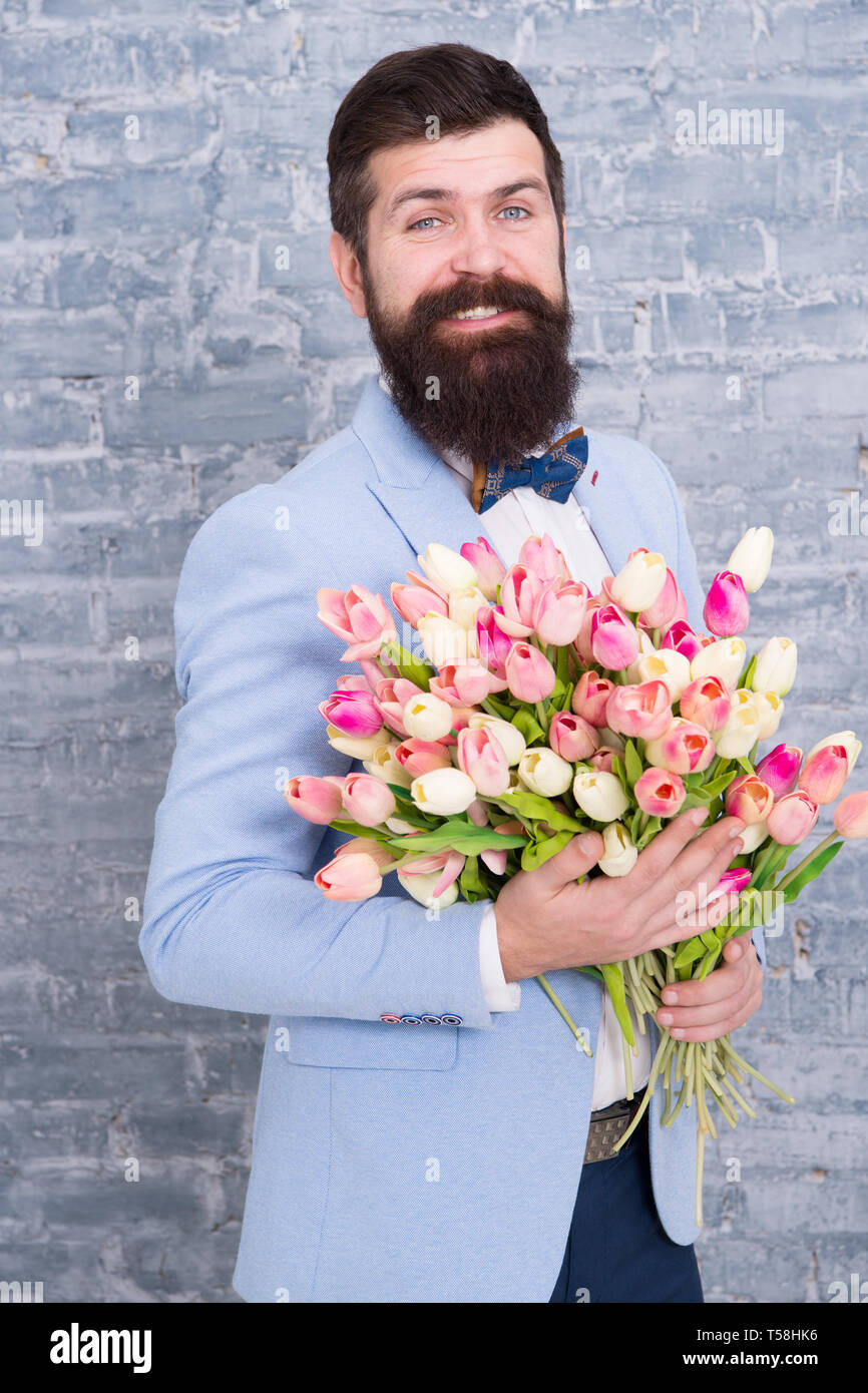 Spring gift. Bearded man hipster with flowers. Bearded man with tulip  bouquet. Flower for March 8. Love date. international holiday. Womens day.  bearded man with happy face. flowers from bearded man Stock, image size:866x1390