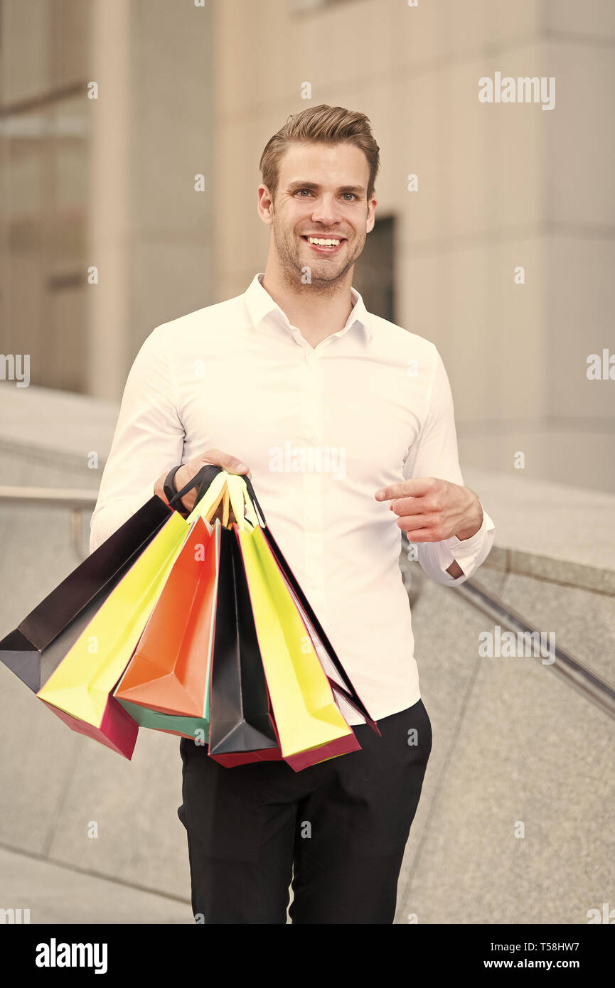 Man formal clothes carry shopping bags. Guy happy carry bunch shopping bags. Profitable deals on black friday. Man hold lot paper bags packages after shopping in mall. Black friday sale concept. Stock Photo