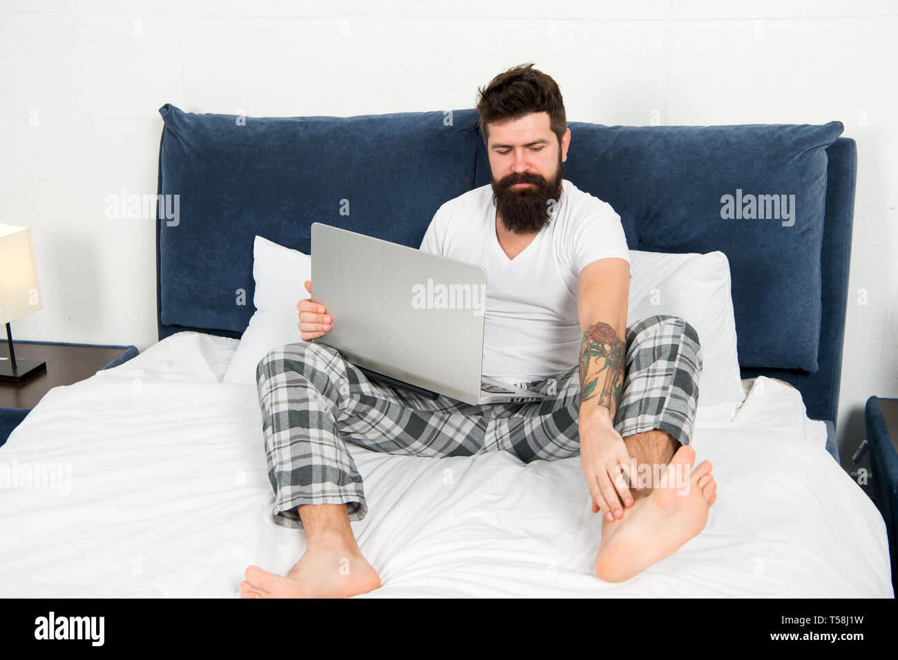 Man surfing internet or working online. Hipster bearded guy pajamas freelance worker. Remote work concept. Online life. Social networks internet addiction. Online shopping. Whole world in his laptop. Stock Photo