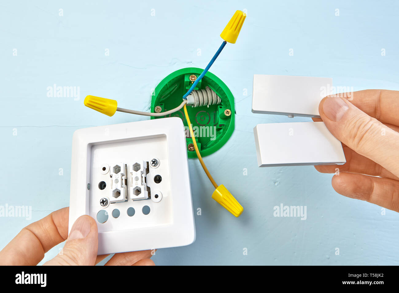 Installation of new button for two-button light switch, round outlet box for wall light on the background. Stock Photo
