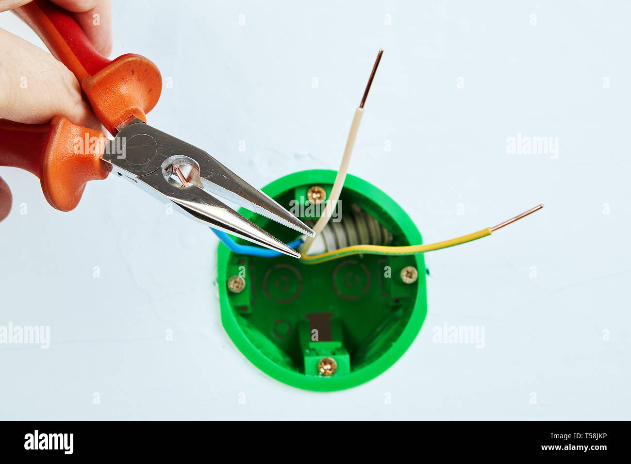 Electrician is installing new round outlet box for wall light with help