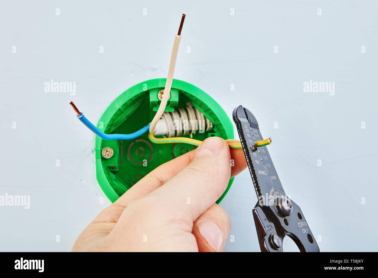 Removing insulation from wires of round outlet box for wall light with