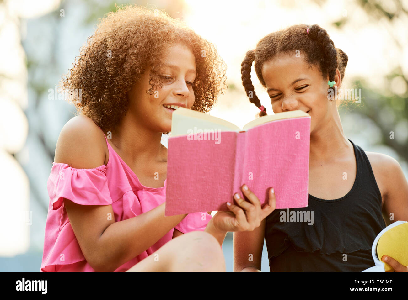 Cheerful black girls reading book Stock Photo