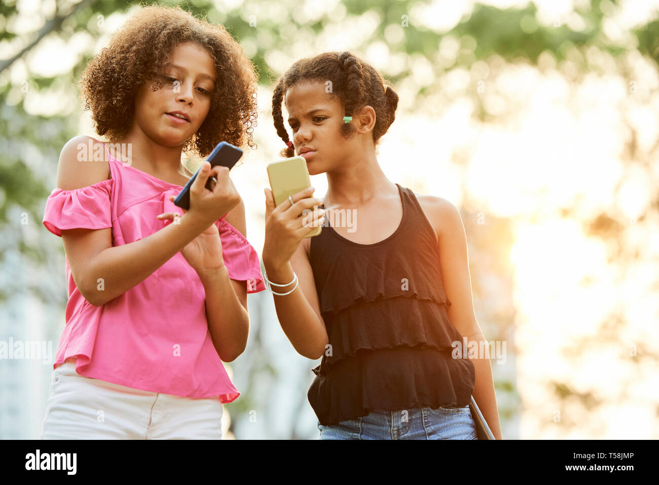 Confused girls checking information on smartphones Stock Photo