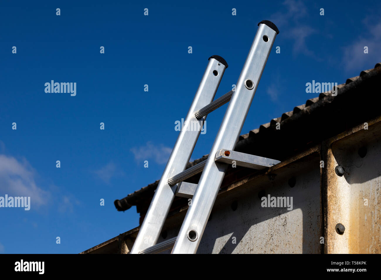 Aluminium ladder securely fastened at top to steelwork to comply with